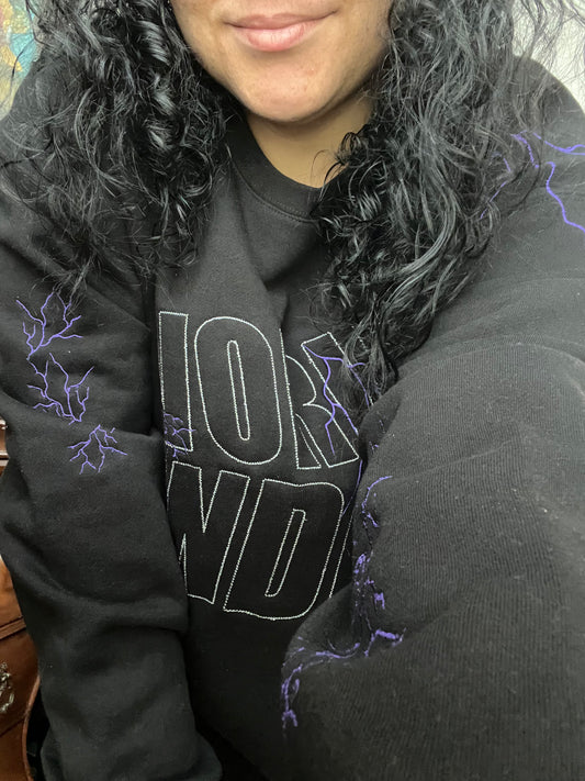Person wearing a black hoodie with 'WORLD ENDER' text and purple lightning designs.